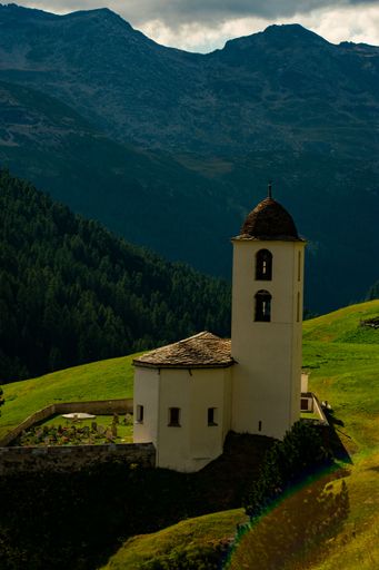 A vertical shot of Reformierte Kirche Avers-Cresta and mountains in Avers, Switzerland