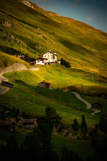 A vertical shot of a rural house with mountains and a cloudy sky in the background