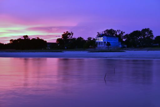 A single building on the shore surrounded by a lot of trees near the beautiful sea