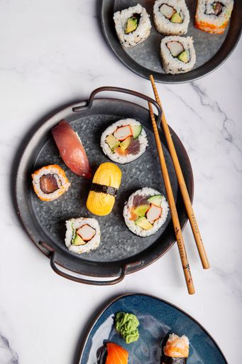 A top view of California Sushi Rolls and Nigiris on plates with chopsticks