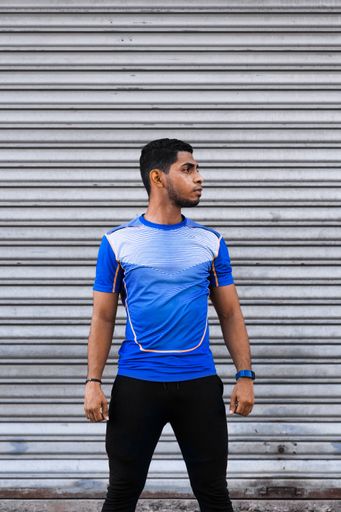 A vertical shot of a young Hispanic male standing straight in front of a garage door