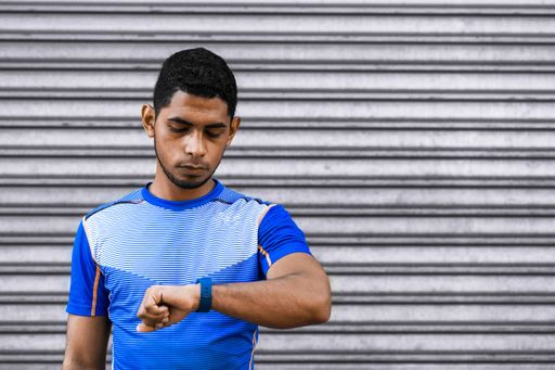 A Hispanic male looking at his calorie watch tracker after a training