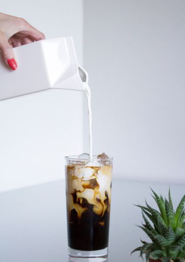 hand holding a cup of coffee with a straw on a white background wallpaper