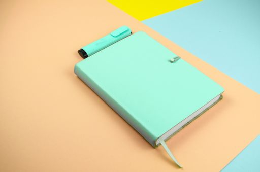 A high angle shot of a green notebook and highlighter - education concept