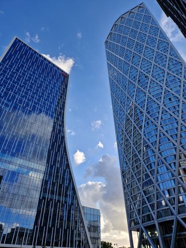 A low angle shot of modern tall buildings udner a light blue sky