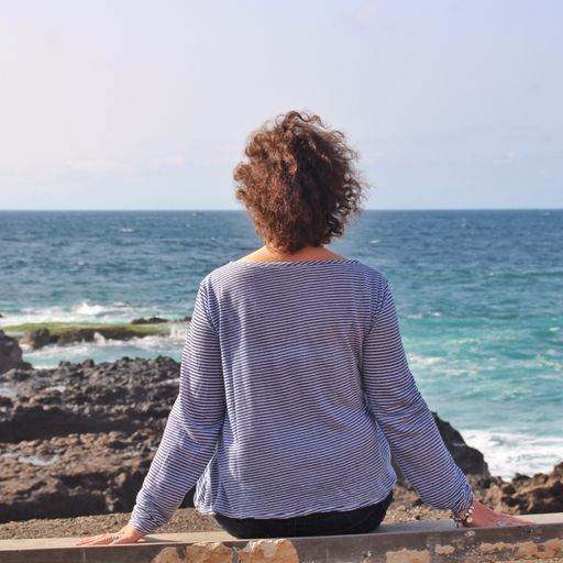 A lonely female sitting on a rock and enjoying the beautiful view of the sea