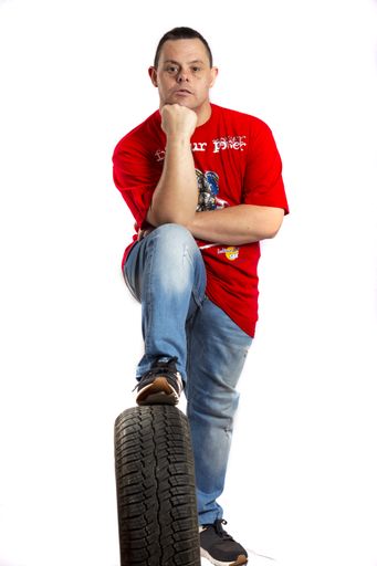 A male with down syndrome posing in photo studio stepping on car wheel
