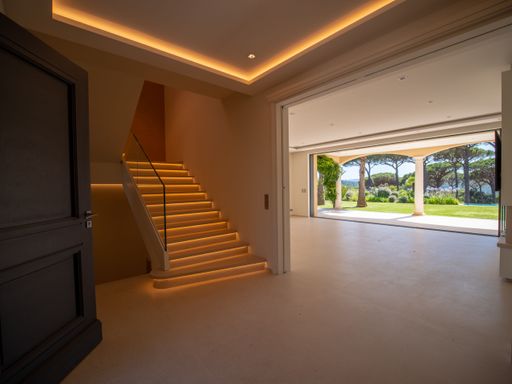 An interior of a luxurious villa with illuminated stairs and a view of a beautiful garden