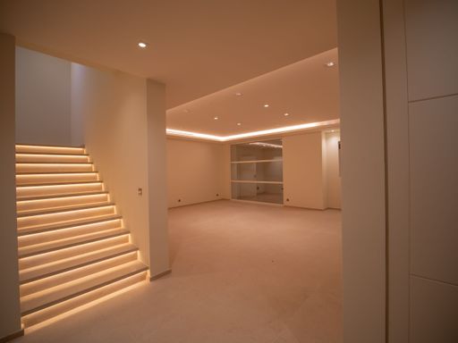 Large bright room without windows with LEDs on the ceiling, a bright staircase, and cupboards