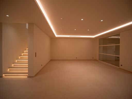 Large bright room without windows with LEDs on the ceiling, a bright staircase, and cupboards