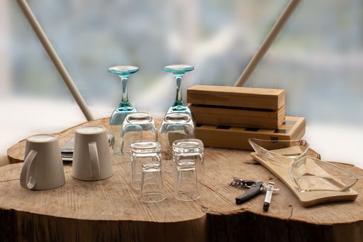 A high angle closeup shot of different types of glasses on a wooden table with a wine opener on it