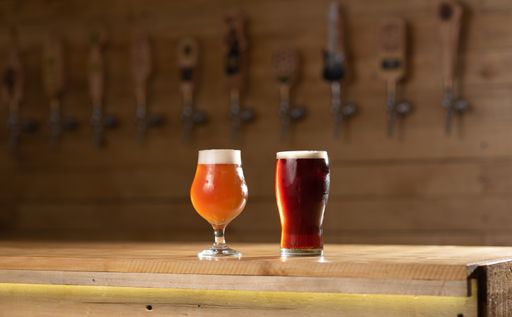 Fresh draft beer freshly served on the yellow illuminated wooden counter and draft equipment on the back