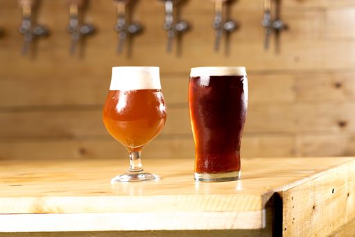 Fresh draft beer freshly served on the yellow illuminated wooden counter and draft equipment on the back