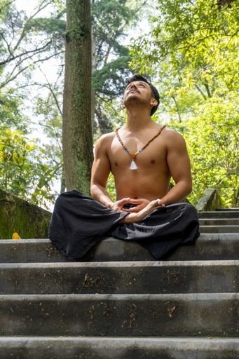 A vertical shot of a young Mexican male in a free pose of meditation looking up