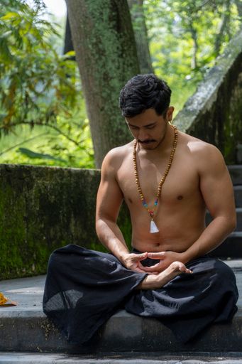 A vertical shot of a young Mexican male in a free pose of meditation looking down