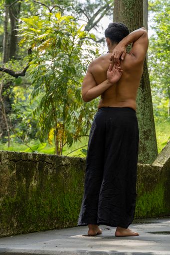 A young Hispanic man practicing Gomukhasana yoga pose in the forest in Mexico, Gualdajara
