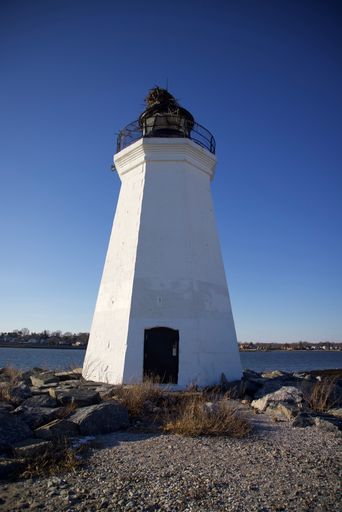 A lighthouse building surrounded by rocks in background of sea in Bridgeport