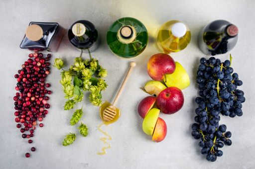 A top view of different types of drinks with fruits and honey wooden spoon