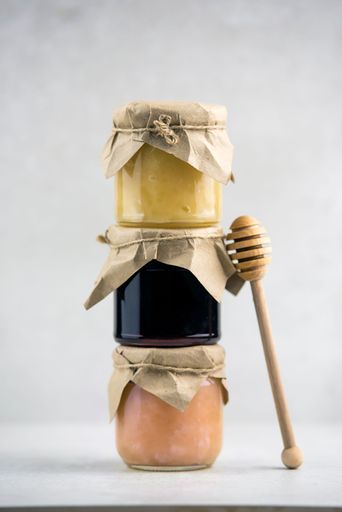 The Jars of honey and jams on top of each other, honey dipper, vertical