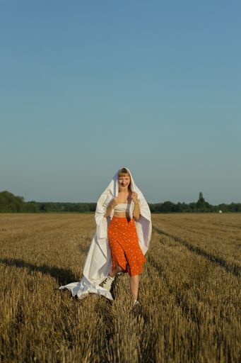 Girl running on field in orange pants holding white sheet