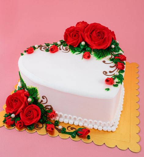 A heart-shaped white cake covered by red roses