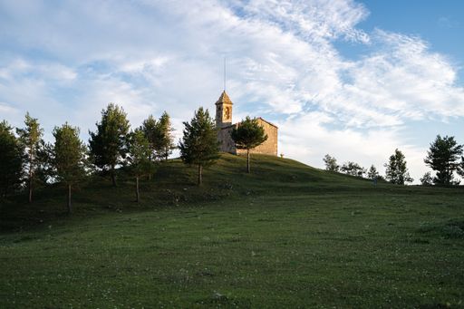 The Santuari de Santa Maria del Puig-aguilar on top of a green heel under the cloudy sky