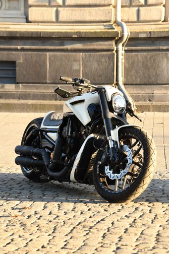 A vertical shot of a white chopper motorcycle parked under the sunlight