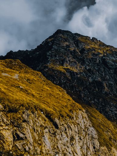 A vertical shot of mountains and hills covered with grass on a sunny day
