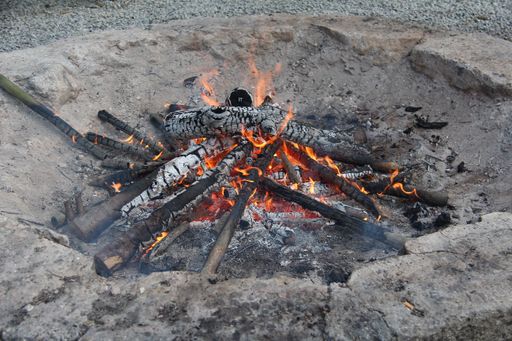 A closeup of a campfire place with burning wood logs
