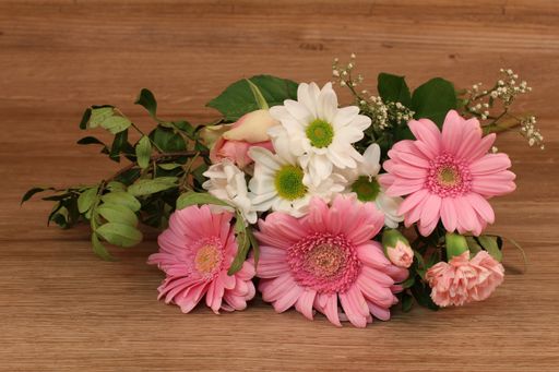 A closeup shot of cute flowers bouquet on a wooden surface