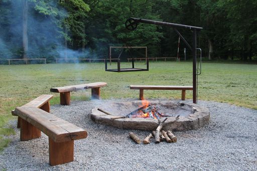 A camping place for a bonfire with burning wood logs and bunches