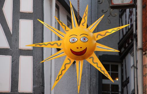 A closeup shot of a smiling sun decoration hanging on a street