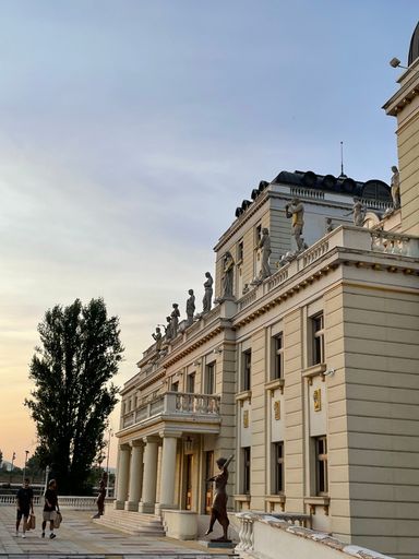 A vertical shot of a theater building with a blue sky background in Skopje