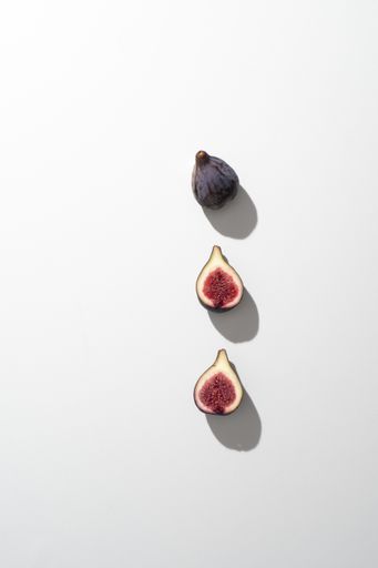 A vertical closeup shot of figs slices in a row isolated on a white background