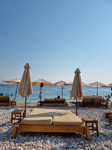 A vertical of beach umbrellas and mattresses on the seashore