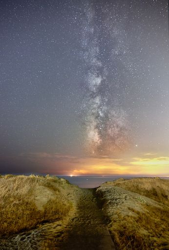 A vertical shot of a trail on the beach in Marbella, Spain under the milky way in the night sky