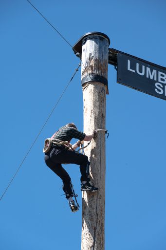 A professional working in a high visibility uniform and adjusting a street sign on a pole in a suburban area