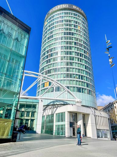 A vertical shot of a man standing in front of the Rotunda.  Birmingham, England.