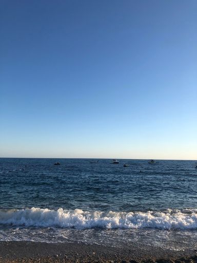 A vertical shot of the seascape with foamy waves against a blue sky