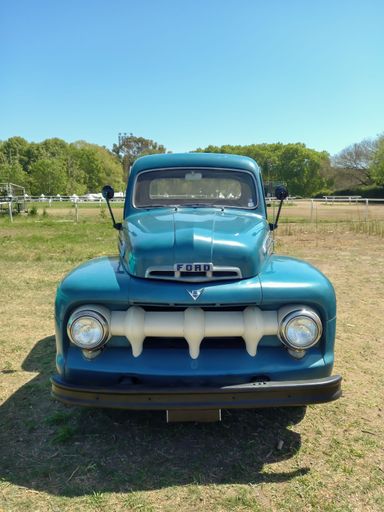 old blue utility 1951 Ford F 1 pickup truck in countryside. Sales service genuine parts logo on door. Front view. Autoclasica 2022 classic car show