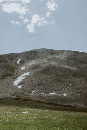 A vertical shot of the green vale and mountain against the background of blue sky.