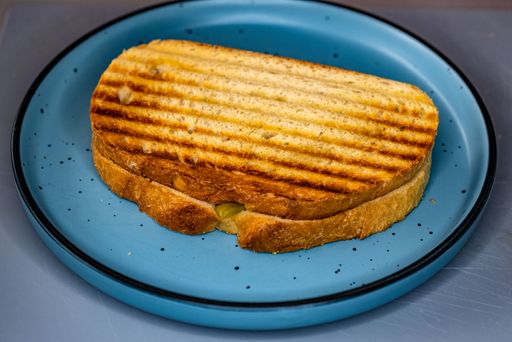 A closeup of the panini in the blue plate on the gray background