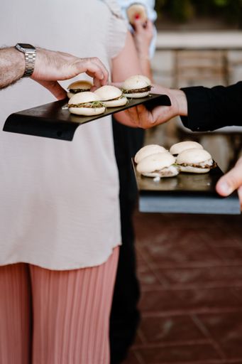A vertical shot of a person taking hamburgers from a black plate indoors