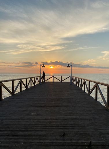 A vertical shot of a wooden pier at the beach at a mesmerizing soft sunset