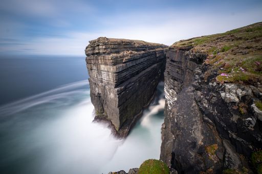 Diarmuid and Grainnes Rock. Long exposure still image during a sunny day with blue sky in the background and sea motion blurred out.