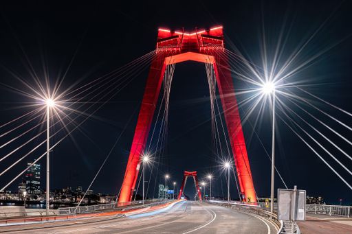 The illuminated Willems bridge in Rotterdam captured at night next to a long exposure of street lights