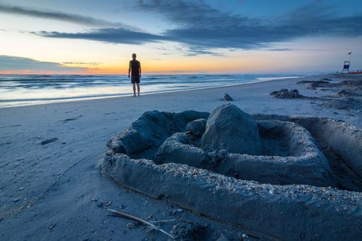 A man standing on the ocean beach near Strand Meer at blue hour sunset