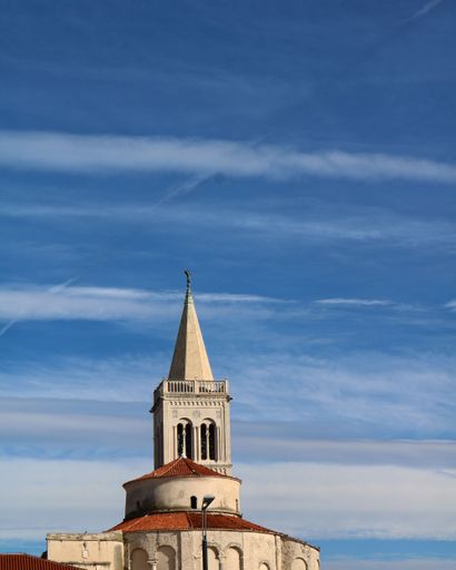 A vertical shot of the bell tower of the Church of St. Donatus with the blue sky in the background