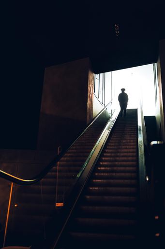 A vertical shot of the person from behind on the underground escalator climbing up