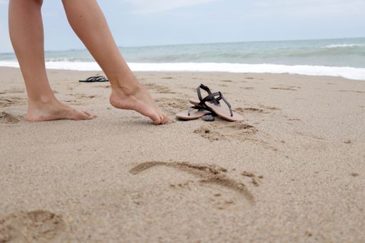 A closeup of a barefoot woman standing on a beach